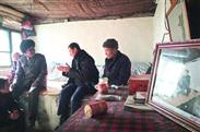 骆驼湾村 来自吉林图们市的王文海（中）正和唐荣斌（左）交谈，右侧是习总书记盘腿坐在炕上的照片。 晨报记者 杨育才